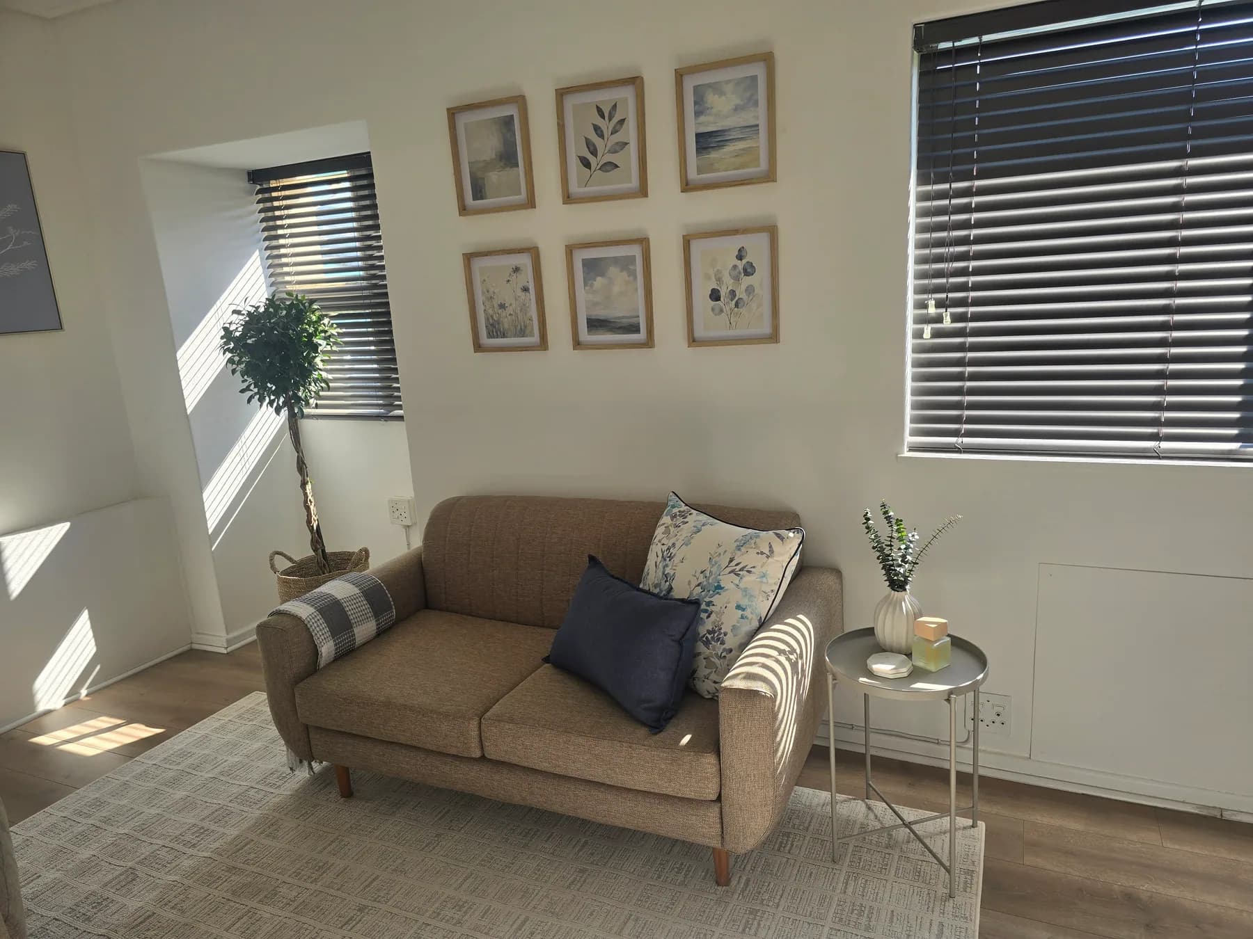 The Mediclinic Paarl consulting room: a soft couch beneath a grid of six framed prints, with a window on either side.